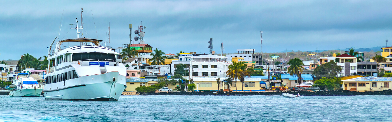 View of Santa Cruz from the coast. The buildings are colorful and close together. There is a large boat in the foreground.
